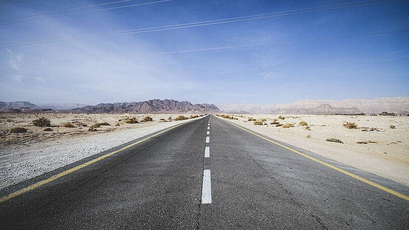 Eine leere gerade Straße in einer kargen Gegend in Israel. 