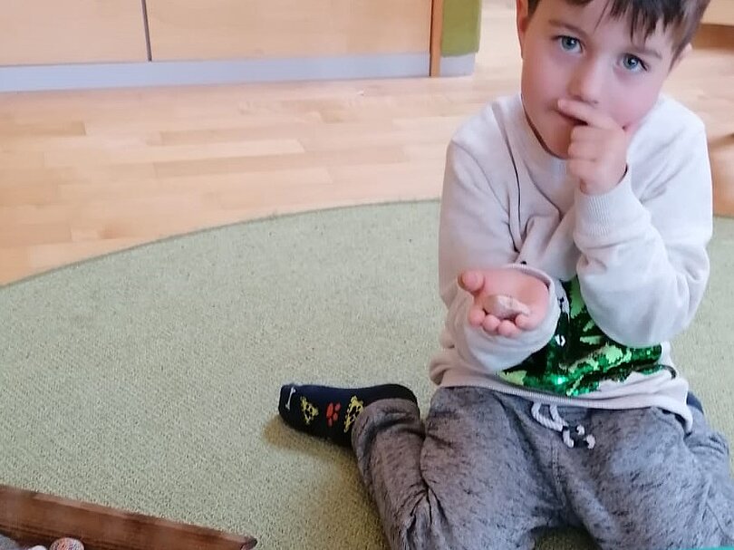 Ein Junge hat einen Stein in der Hand und denkt nach. 