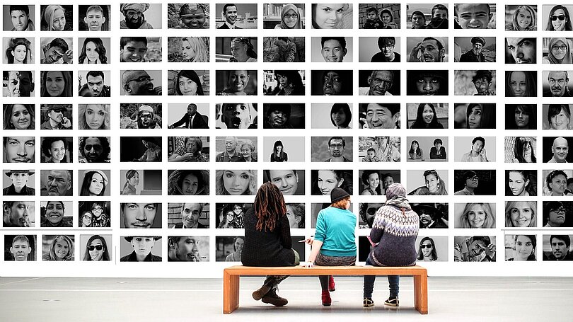Fotowand in einer Kunstausstellung mit vielen menschlichen Gesichtern 