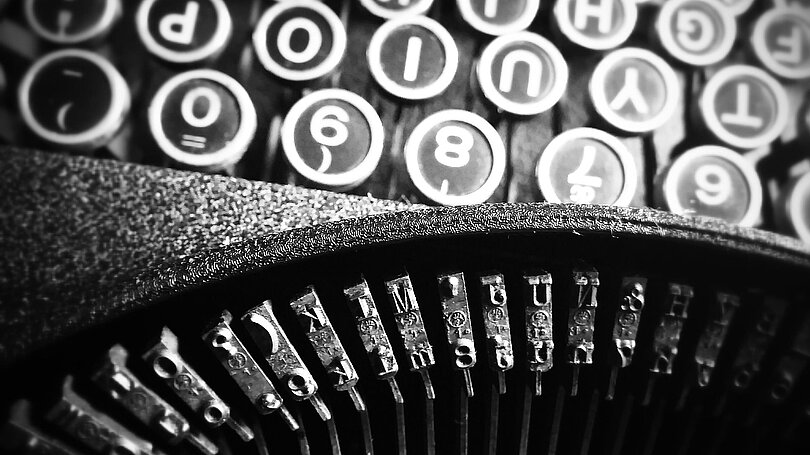 Ein Blick von oben auf eine alte Schreibmaschine. Man sieht die Tastatur und die Typenhebel. 